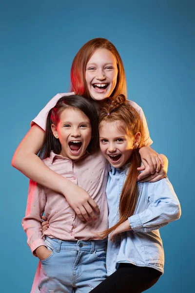 Tre bambini ragazze in piedi insieme su sfondo blu — Foto Stock