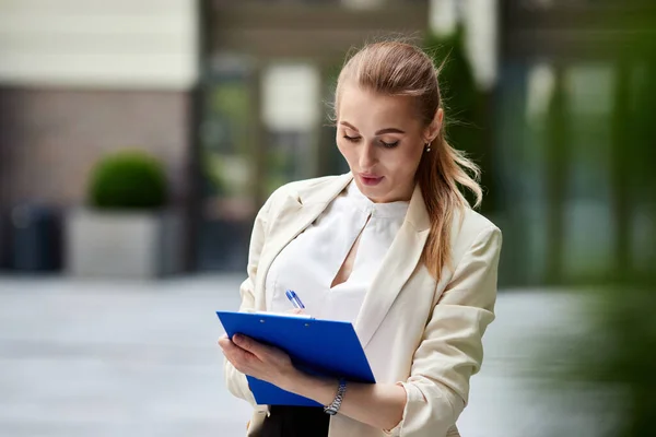 Wanita bisnis cantik dengan clipboard biru outdoor — Stok Foto