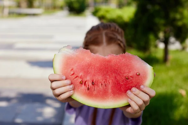 子供の女の子は晴れた日にスイカを食べる — ストック写真