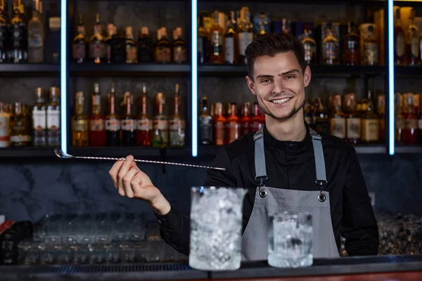 Barman mieszający kostki lodu w kieliszku koktajlowym łyżeczką — Zdjęcie stockowe
