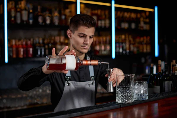 Bartender em avental adiciona ingrediente ao vidro — Fotografia de Stock