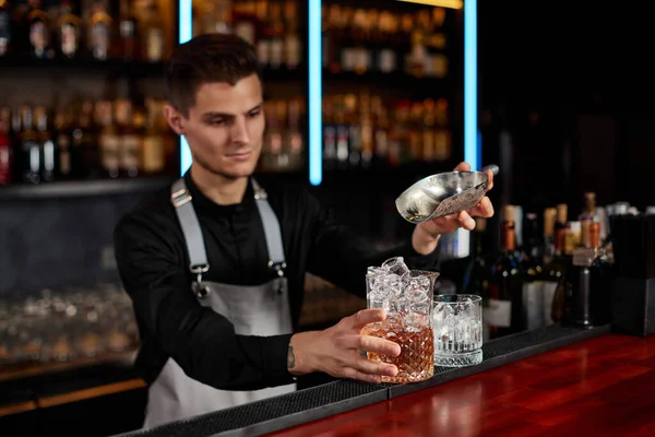 Barman vloží kostky ledu do sklenice s alkoholickým nápojem — Stock fotografie