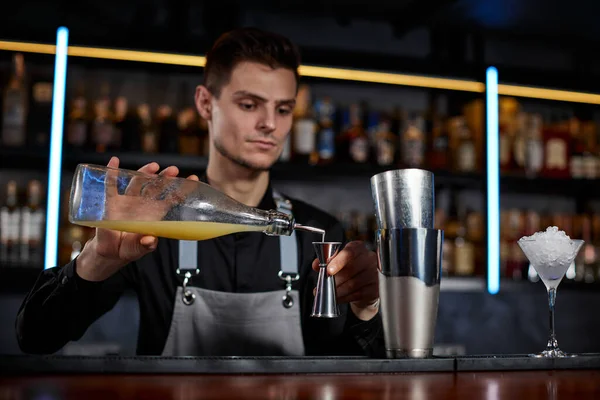 Bartender em avental adiciona ingrediente ao shaker — Fotografia de Stock