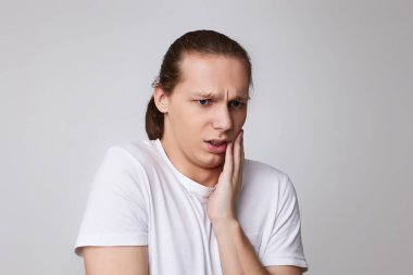 Genç ve mutsuz bir adam kötü diş ağrısı çekiyor.