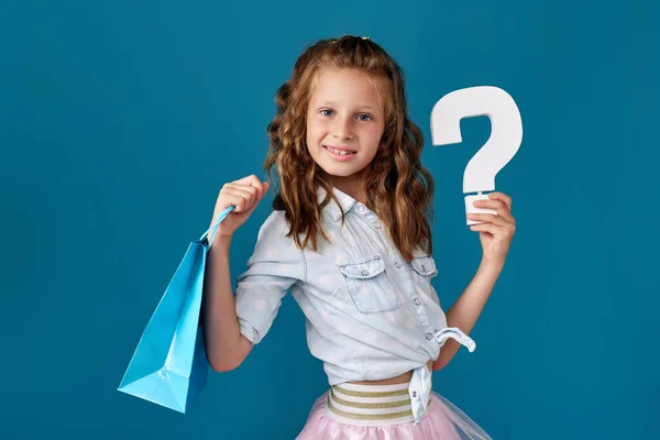어린 소녀가 쇼핑백 과 물음표를 많이 들고 있다 — 스톡 사진