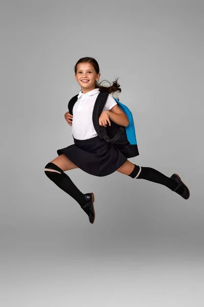 Cute happy schoolgirl jumping up with backpack — Stock Photo, Image