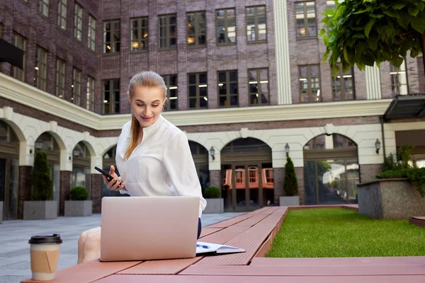 Geschäftsfrau mit Smartphone am Laptop — Stockfoto