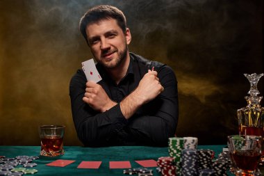 Yeşil masada poker oynayan sakallı kumarbaz.