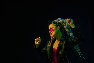 Kırmızı güneş gözlüklü genç kadın dans ediyor.