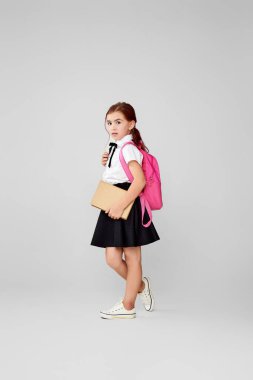 Sırt çantası ve kitap boyu uzun sevimli bir kız öğrenci..