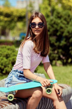 Dışarıda kaykaylı güzel bir kız oturuyor.