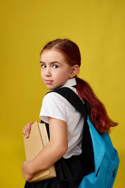 Schattig gelukkig schoolmeisje met rugzak en boek — Stockfoto