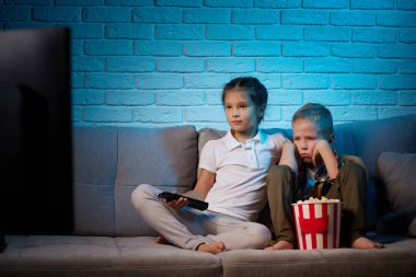 Uzaktan kumandalı iki çocuk televizyon izliyor.