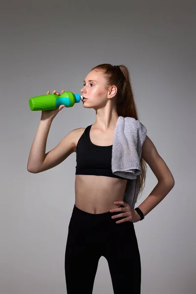Женщина с полотенцем в черной спортивной одежде питьевой воды — стоковое фото