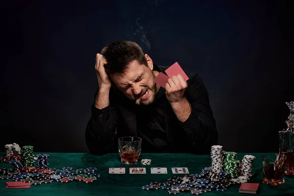 Bearded casino player man playing poker on green table