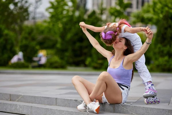 Klein meisje op rolschaatsen en haar moeder in park. — Stockfoto