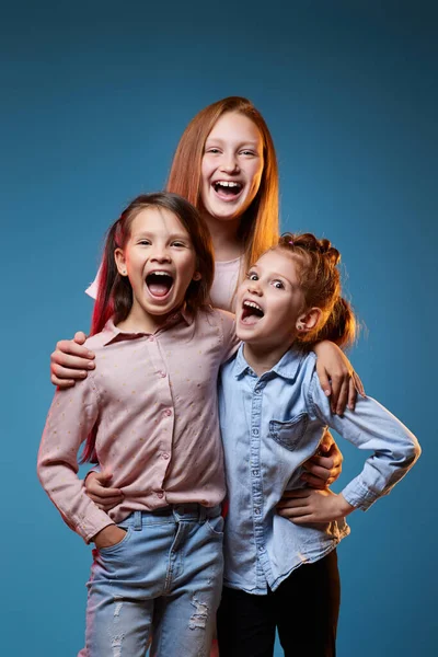 Trois enfants filles debout ensemble sur fond bleu — Photo