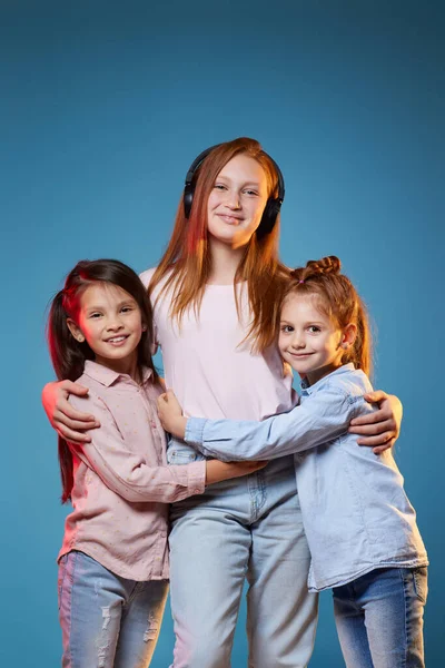 Três crianças meninas de pé juntos no fundo azul — Fotografia de Stock
