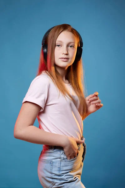 Linda chica adolescente con el pelo rojo en auriculares inalámbricos — Foto de Stock