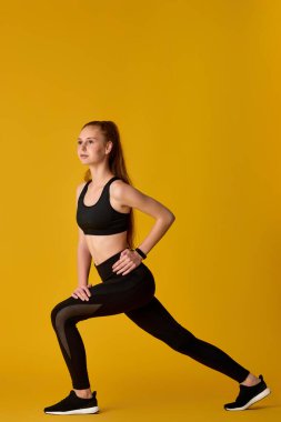 Siyah spor giysili genç kız spor yapıyor.