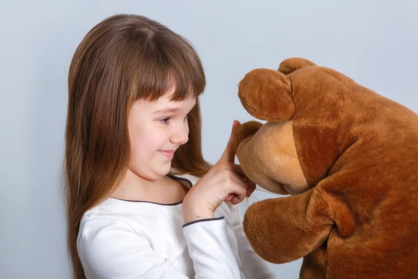 Meisje glimlachend en haar teddy bear knuffelen — Stockfoto