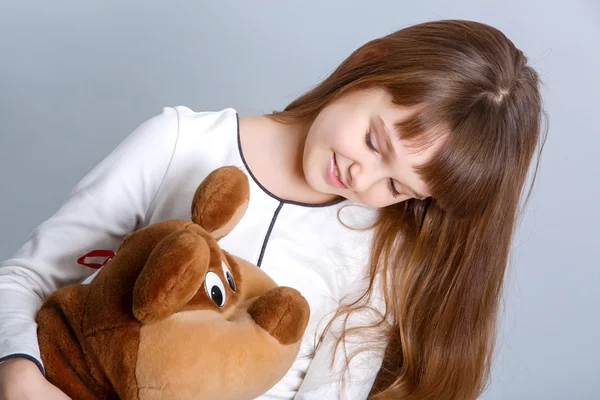 Meisje glimlachend en haar teddy bear knuffelen — Stockfoto