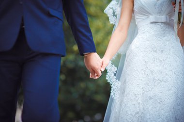 Düğün çifti el ele tutuşuyor.