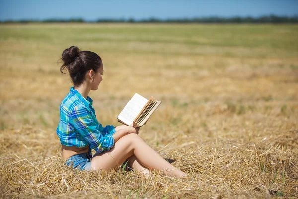 Girl in wheat holding book — Stock Photo, Image