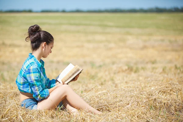 Girl in wheat holding book — Stock Photo, Image