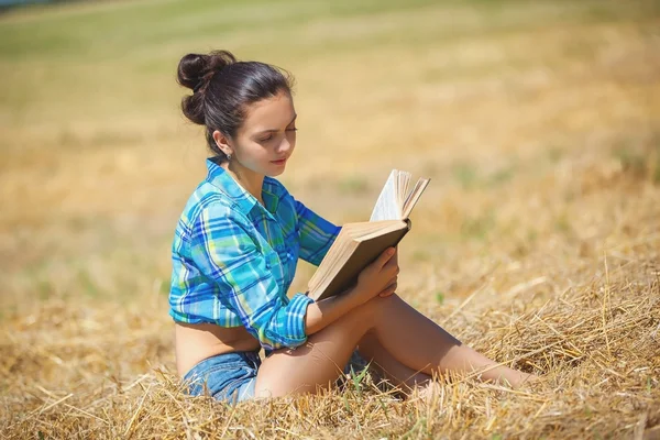 Girl in wheat holding book — Stock Photo, Image