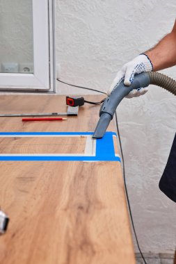 İşçi adam mutfak tezgahındaki lavabo için delik açtıktan sonra yeni mutfağı süpürüyor.