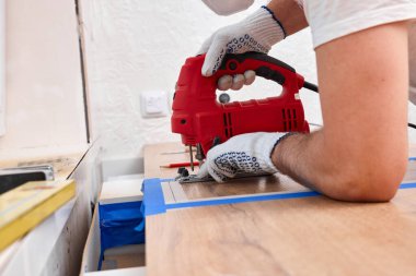 Elektrikli testereli bir tamirci mutfaktaki bir atölyeye testereyle çadır kuruyor.