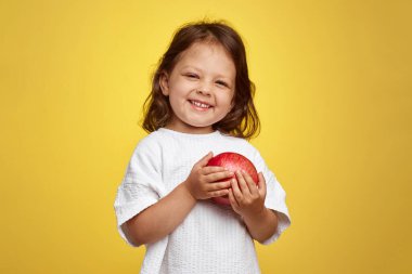 Sarı arka planda elinde nar tutan tatlı bir kız çocuğu..