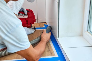 İşçi adam mutfak tezgahındaki lavabo için delik açtıktan sonra yeni mutfağı süpürüyor.