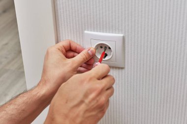 male hands installing electrical wall outlets with a screwdriver at home