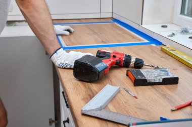 Tamirci yeni bir mutfak kurulumunda çalışıyor ve elektrikli matkap kullanıyor.