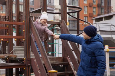 Önemseyen baba, kışın şehir parkında eğlenen çocuğa yardım ediyor.