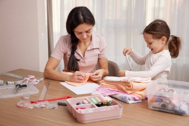 Anne ve küçük kız kaynaşıyor, zanaat becerileri öğreniyor ve el yapımı eşyalar yaratıyor.