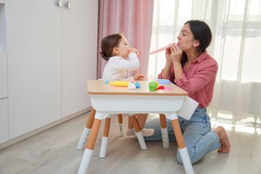 Anne ve kızı küçük bir masada parti verenleri kutluyor ve onlarla oynuyorlar.