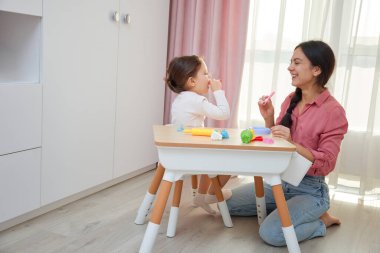 Anne ve kızı küçük bir masada parti verenleri kutluyor ve onlarla oynuyorlar.
