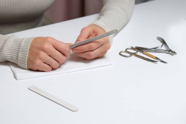 Kadın manikür yaparken tırnak törpüsü kullanıyor.