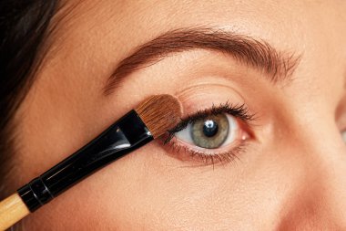Kozmetik göz farı süren bir kadın fırça kullanıyor.