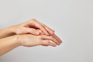 Kadın elleri nazikçe dokunur, beyaz arka planda cilt suyu, bakım ve sağlığını sembolize eder.