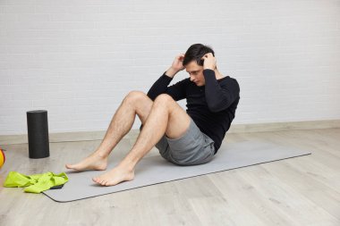 Man exercising abdominal muscles on grey mat, staying fit with a home workout
