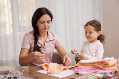Anne ve küçük kız kaynaşıyor, zanaat becerileri öğreniyor ve el yapımı eşyalar yaratıyor.
