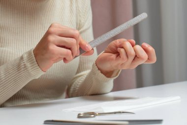 Kadın manikür yapıyor, tırnaklarını törpülüyor kişisel bakım ve güzellik tedavisi için