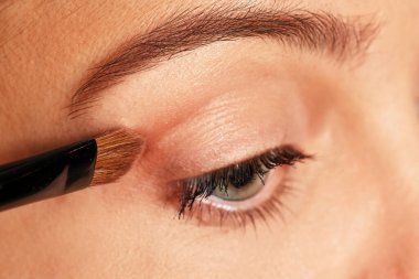 Kozmetik göz farı süren bir kadın fırça kullanıyor.
