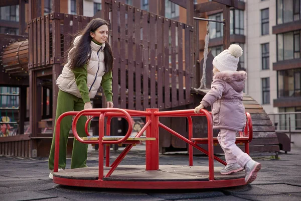Anne ve kızı bir şehir parkında atlıkarıncada birlikte oynuyorlar.