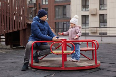 Baba ve kızı atlıkarıncada oynuyorlar, kaynaşıyorlar ve eğleniyorlar.