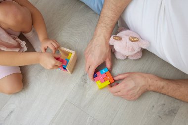 Baba ve kızı evde oturmuş renkli oyuncaklarla oynarken birbirlerine bağlanıyorlar.